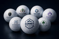 Seven custom UV-printed golf balls with corporate logos on a navy backdrop